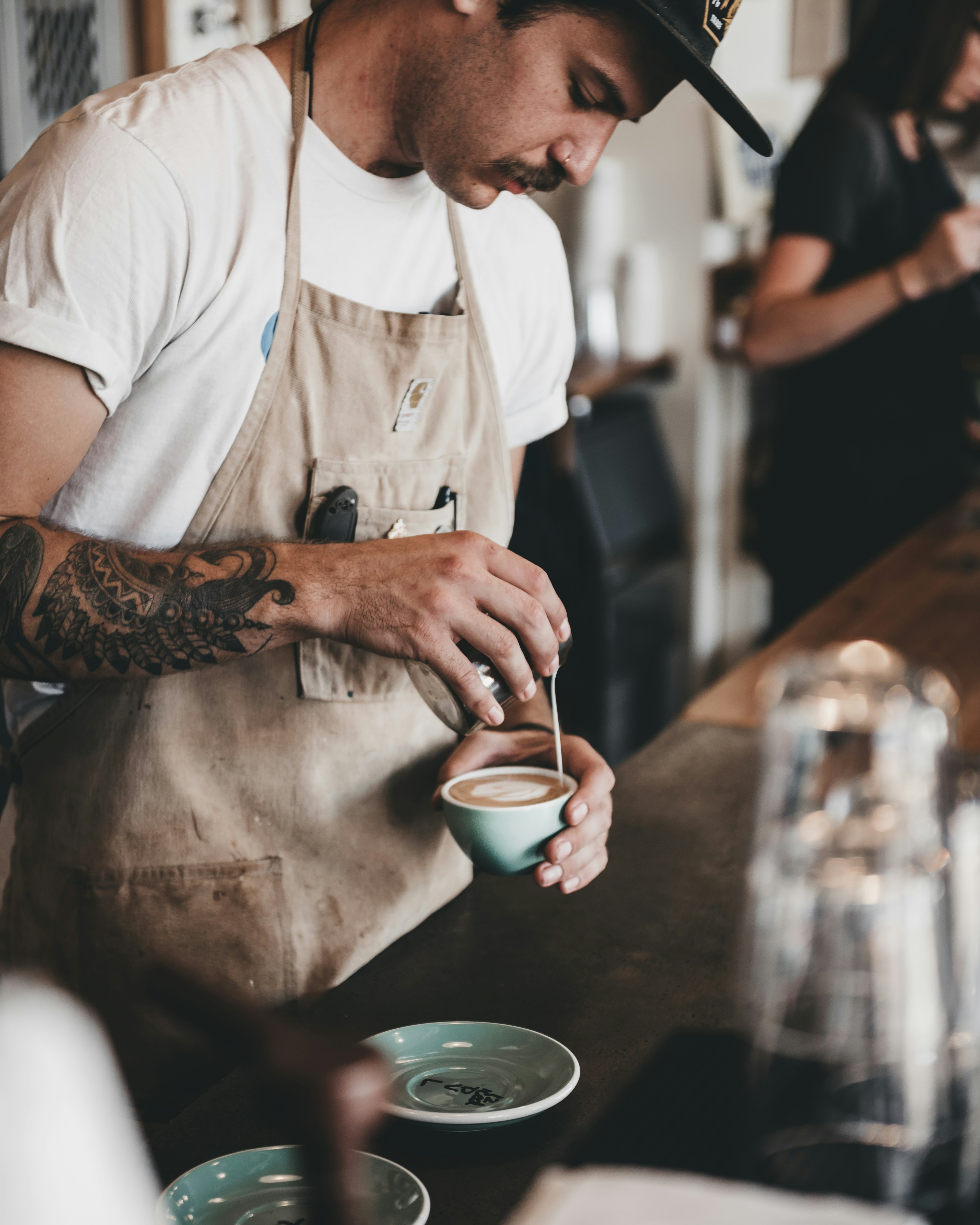 A barista pouring latte art into a cup